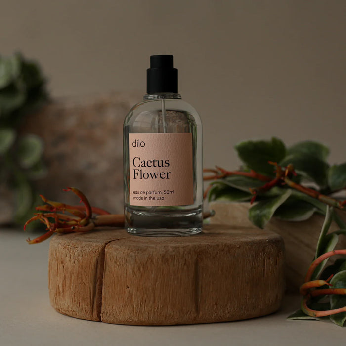 Dilo Cactus Flower perfume bottle on a wooden platform with plants in the background