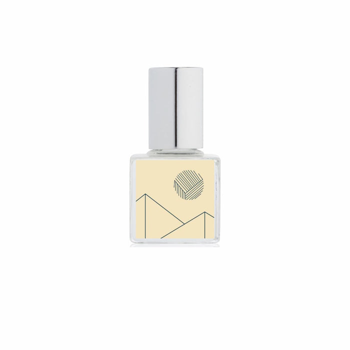 A clear glass bottle of Kelly + Jones Mezcal Blanca perfume oil with a silver cylindrical cap and a pale yellow label featuring a minimalist black geometric line design, centered on a white background.